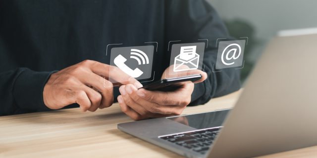 Businessman using laptop and smartphone with contact icons on virtual screen. searching web, browsing information, Contact us or Customer support hotline people connect.